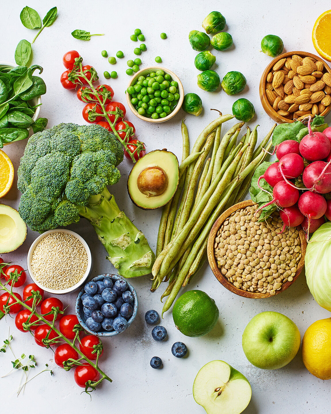 Assortiment coloré de fruits, légumes, légumineuses et oléagineux frais sur une surface blanche