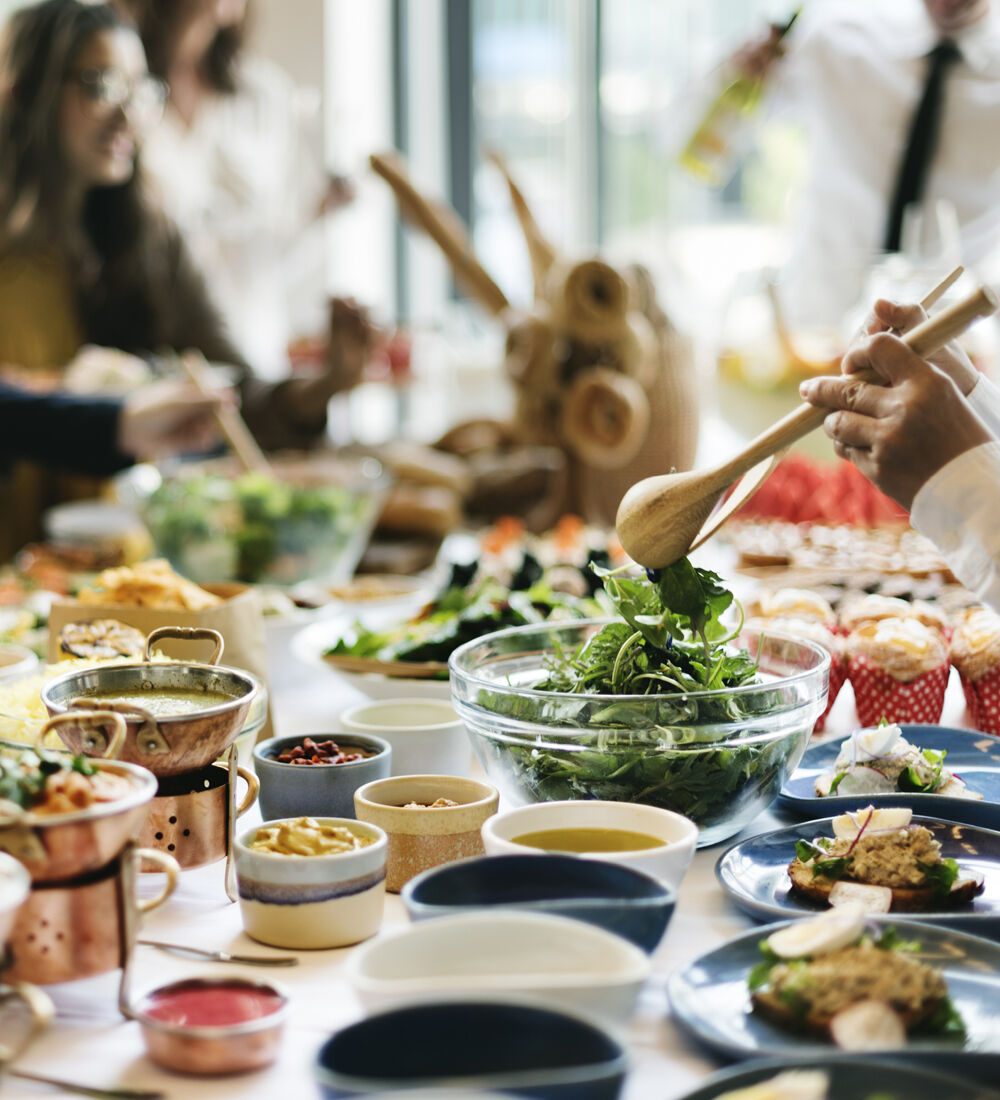 Table conviviale garnie de plats variés incluant des légumes frais et des préparations culinaires