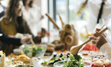 Personnes partageant un repas convivial avec des plats variés à base de légumes et d'autres ingrédients