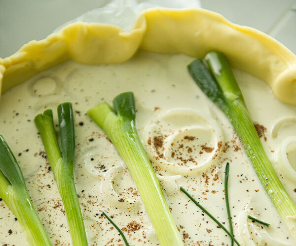 préparation recette quiche à la ciboule, oignon ciboule placé dans la pâte brisée avec crème