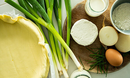 Ingrédients de la recette de quiche à la ciboule. pâte, farine, oignon doux, crème, lait, oeuf, fromage de chèvre, oignon ciboule