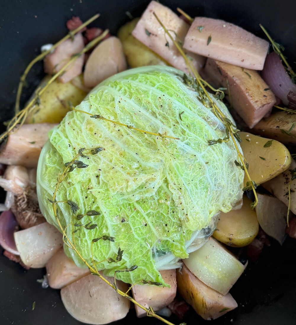 Chou farci accompagné de légumes d’hiver dans une cocotte, garni de thym frais pour une cuisson savoureuse