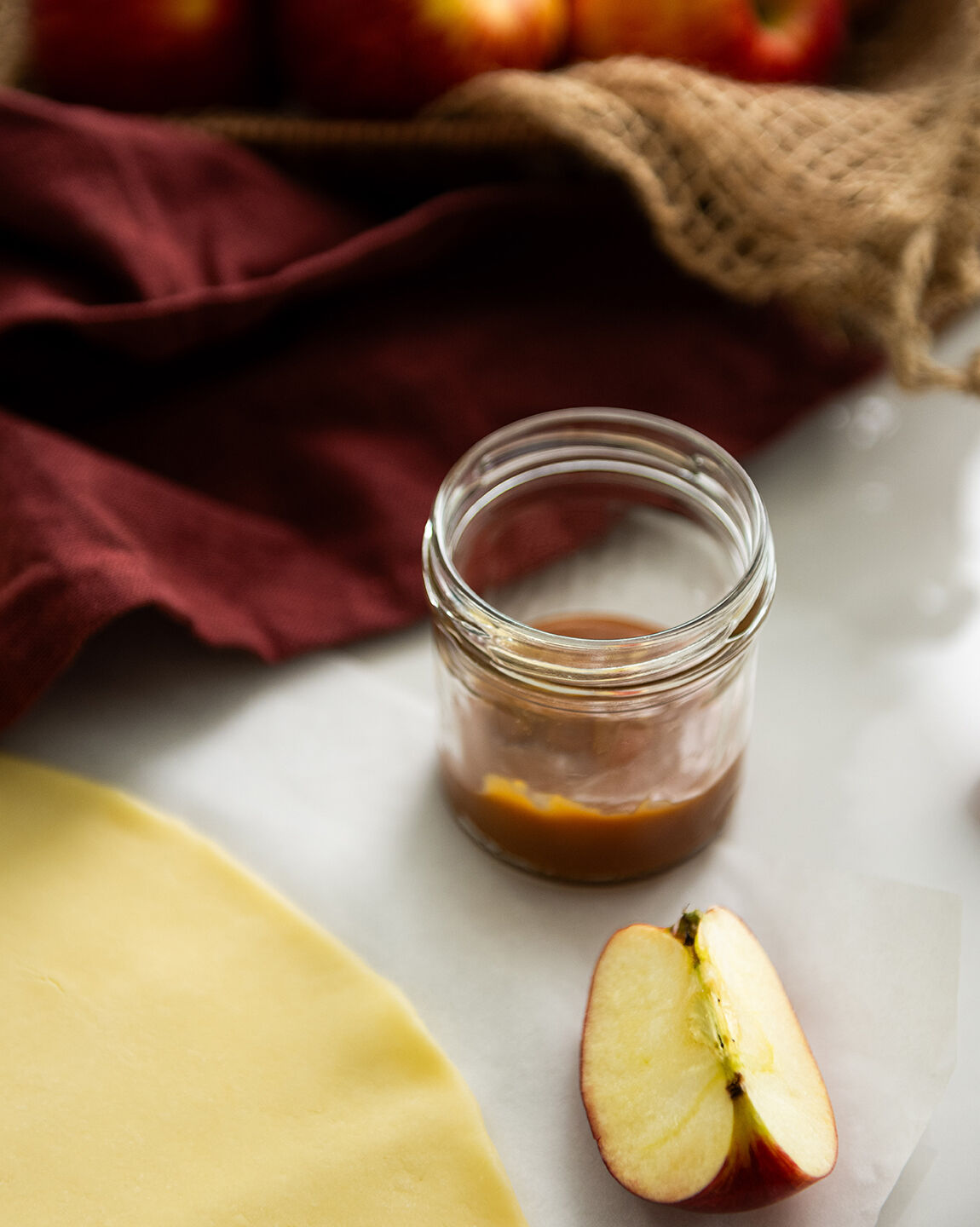Préparation des ingrédients pour le douillon de pomme : pâte étalée, caramel dans un bocal, et quartier de pomme fraîche