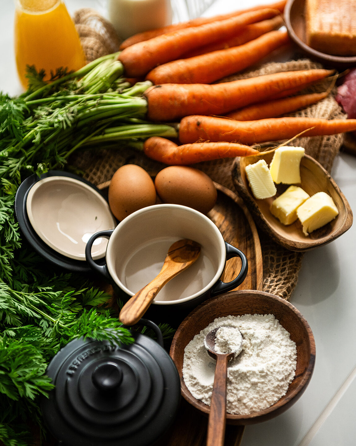 Préparation des ingrédients pour soufflé de carottes avec des carottes fraîches, œufs, farine, beurre, et ustensiles de cuisine