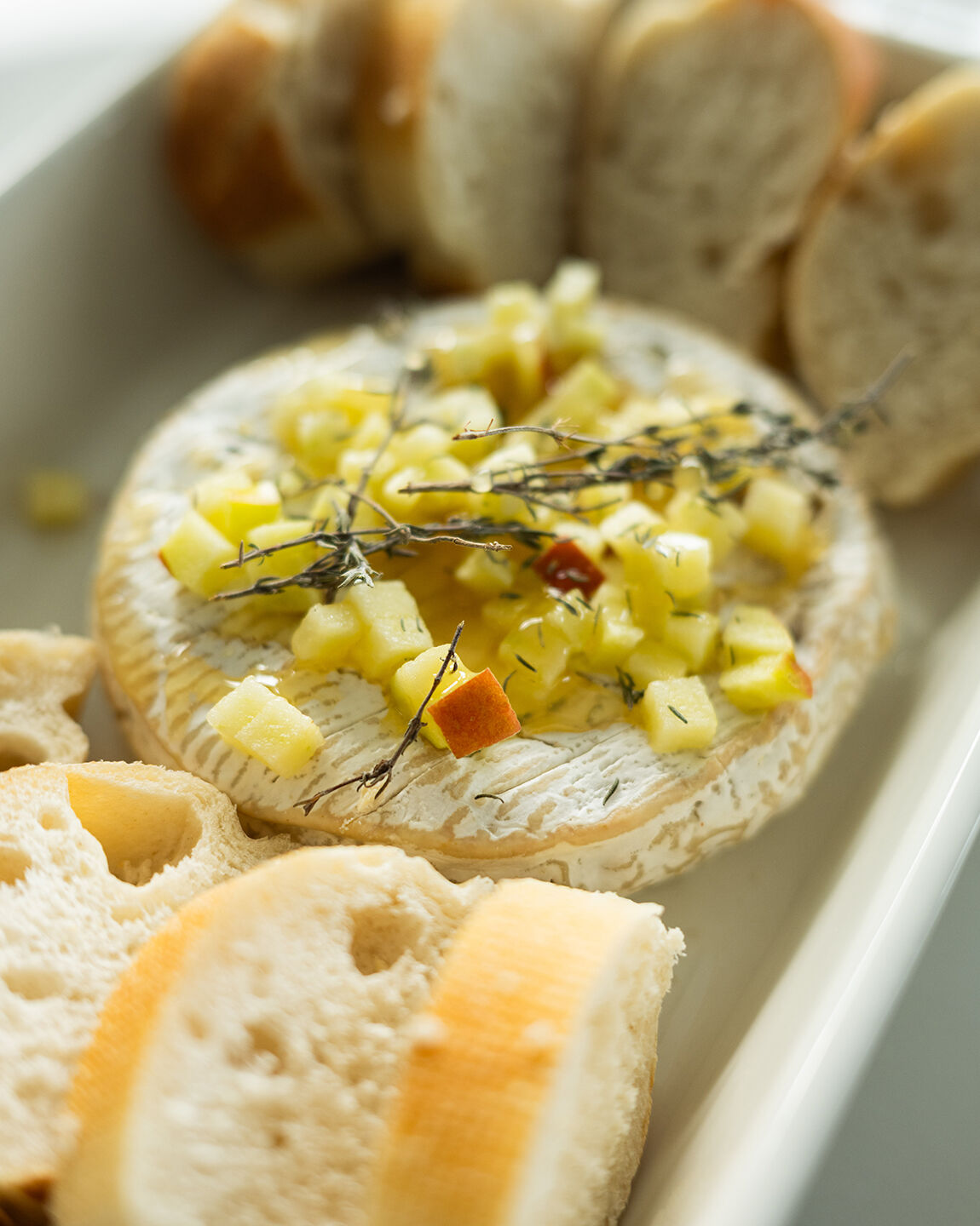 Camembert belge préparé avec du miel, des morceaux de pomme et du thym avant cuisson pour un apéro hivernal gourmand !